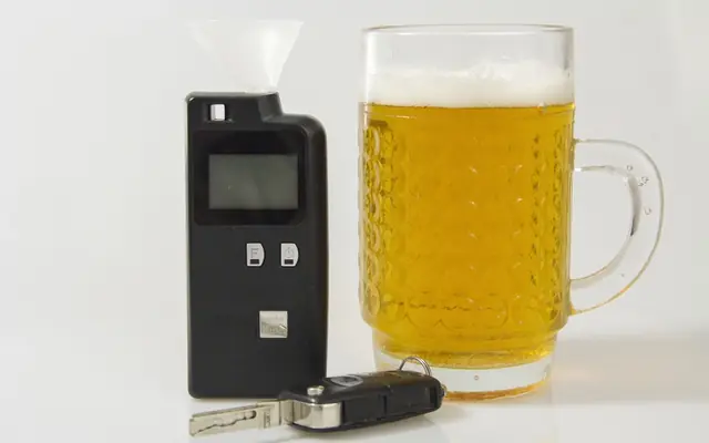 Alcotest, vaso de cerveza y llaves de un auto sobre una mesa