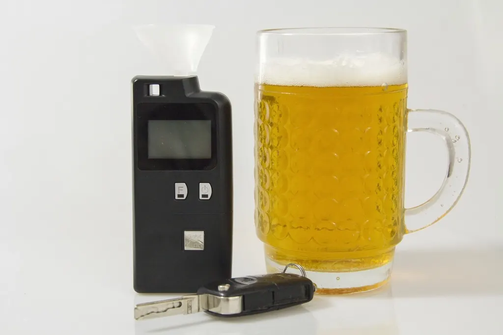 Alcotest, vaso de cerveza y llaves de un auto sobre una mesa