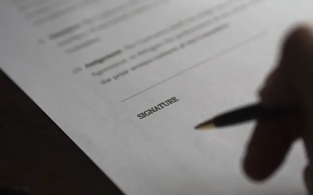 Mano firmando un documento con un lápiz