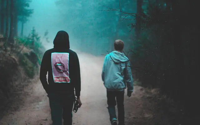 Dos jóvenes caminando de espaldas en un sendero