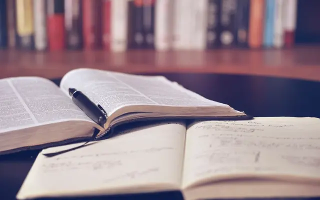 Libro abierto con anotaciones sobre una mesa de biblioteca